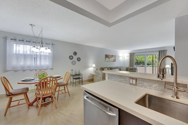 kitchen featuring light tile patterned flooring, sink, hanging light fixtures, a textured ceiling, and dishwasher