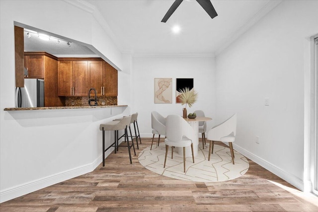 dining space with crown molding, ceiling fan, sink, and hardwood / wood-style floors