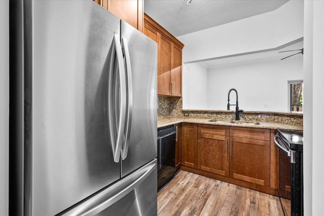 kitchen with electric range oven, stainless steel refrigerator, black dishwasher, sink, and light stone countertops