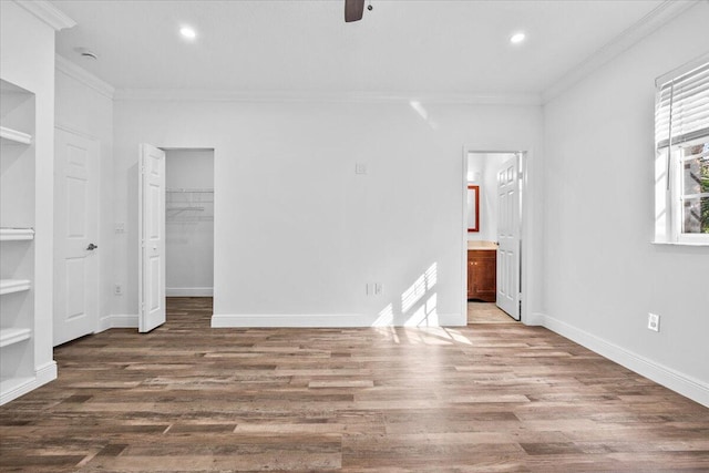 unfurnished bedroom with ensuite bath, ornamental molding, dark hardwood / wood-style floors, and a spacious closet