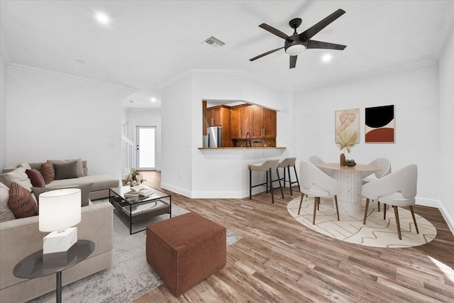 living room featuring ornamental molding, ceiling fan, and light hardwood / wood-style flooring