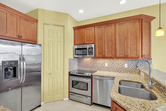 kitchen featuring sink, appliances with stainless steel finishes, backsplash, hanging light fixtures, and light stone counters