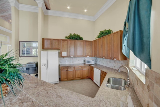 kitchen featuring sink, tasteful backsplash, light tile patterned floors, a towering ceiling, and white appliances