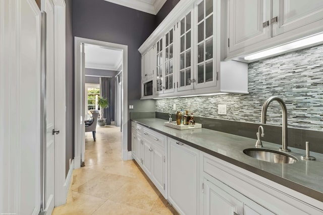 kitchen with sink, light tile patterned floors, ornamental molding, white cabinets, and backsplash