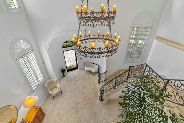 carpeted entrance foyer with a towering ceiling, a wealth of natural light, and a notable chandelier