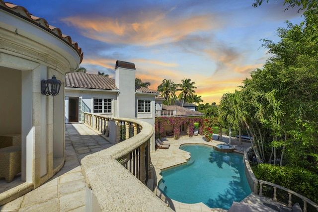 pool at dusk featuring a patio area