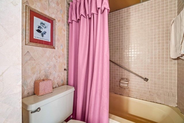 bathroom featuring toilet, shower / bathtub combination with curtain, and tile walls