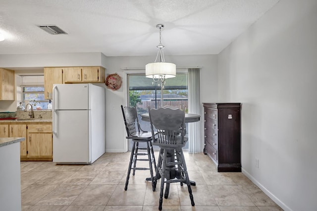 tiled dining space with sink and a textured ceiling