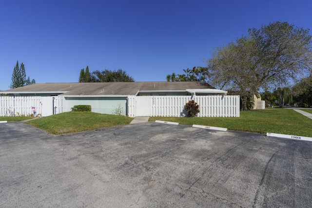 view of front facade with uncovered parking, fence, and a front lawn