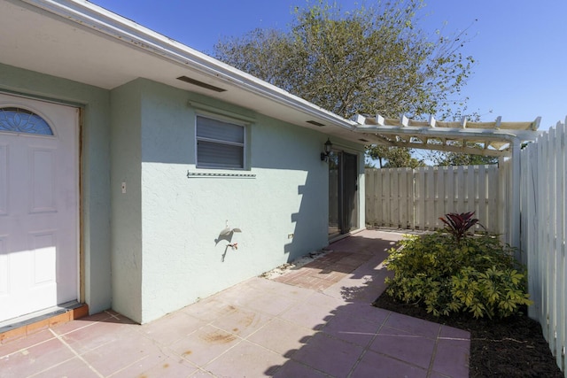 view of side of home with a patio, fence, and stucco siding