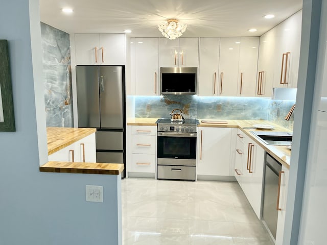 kitchen featuring sink, butcher block countertops, white cabinetry, tasteful backsplash, and stainless steel appliances