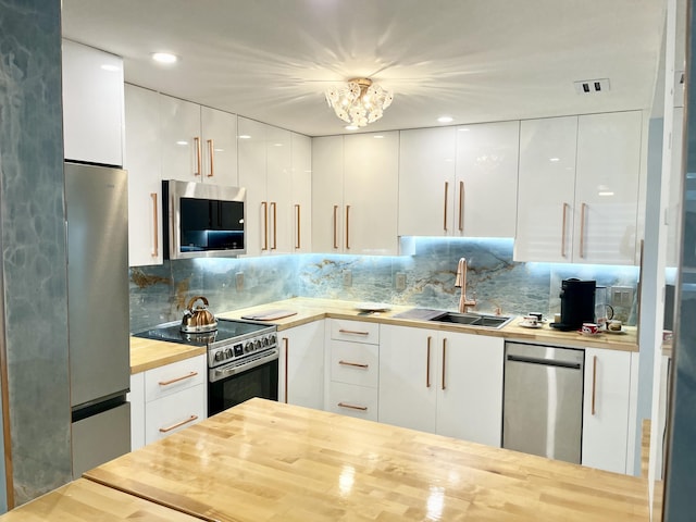 kitchen with sink, white cabinetry, stainless steel appliances, tasteful backsplash, and wood counters