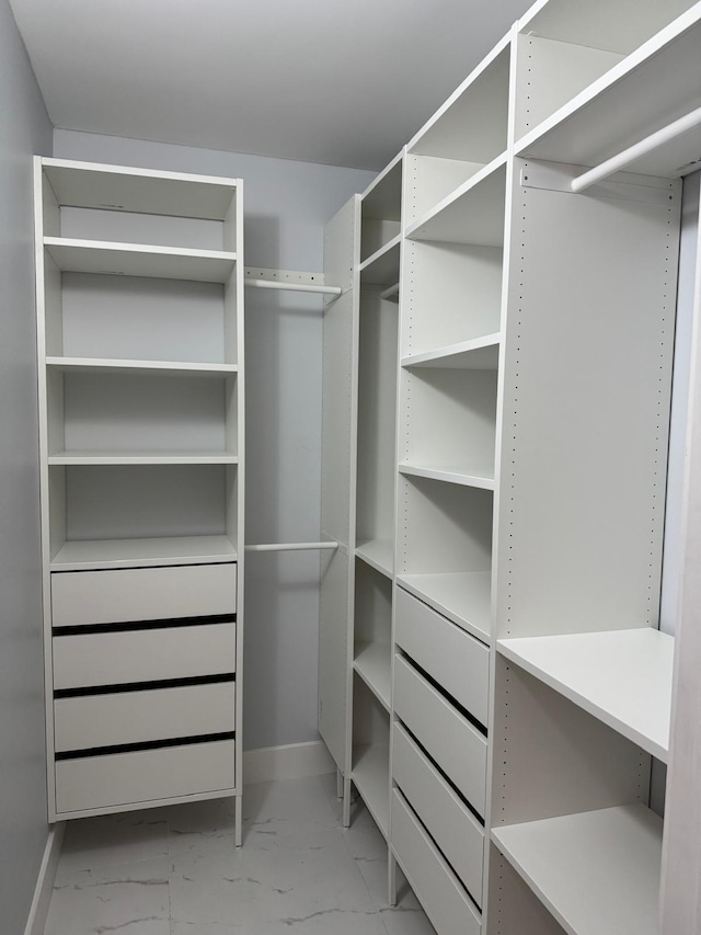 walk in closet featuring marble finish floor