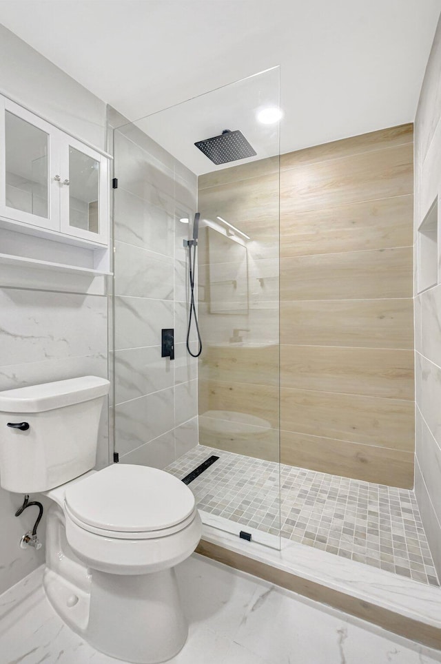 bathroom featuring toilet, marble finish floor, and a walk in shower