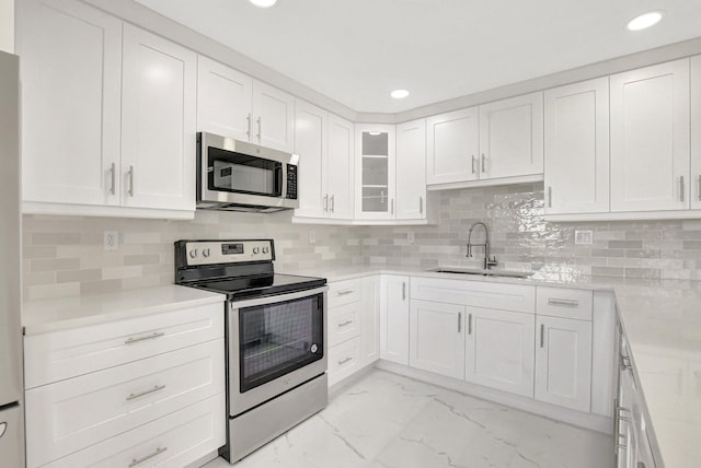 kitchen featuring appliances with stainless steel finishes, tasteful backsplash, white cabinetry, sink, and light stone countertops