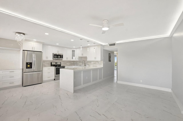 kitchen featuring appliances with stainless steel finishes, decorative light fixtures, tasteful backsplash, white cabinetry, and kitchen peninsula