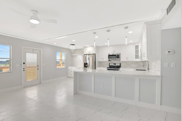 kitchen featuring appliances with stainless steel finishes, decorative light fixtures, sink, white cabinets, and kitchen peninsula