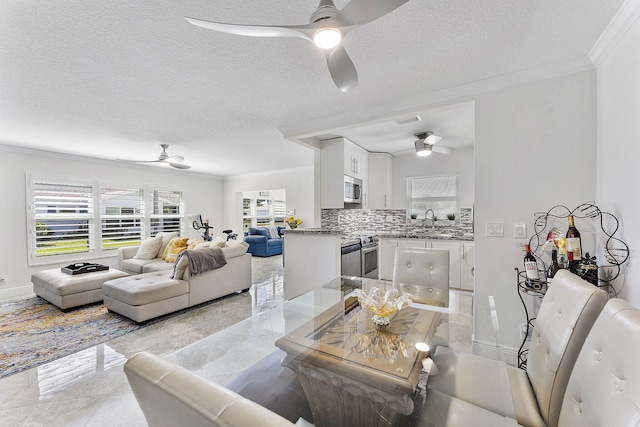 living area with a textured ceiling, crown molding, and ceiling fan