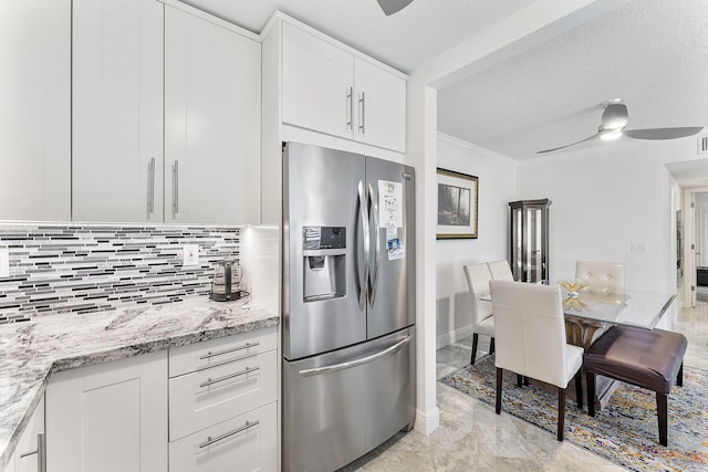 kitchen with a ceiling fan, white cabinets, ornamental molding, stainless steel refrigerator with ice dispenser, and backsplash