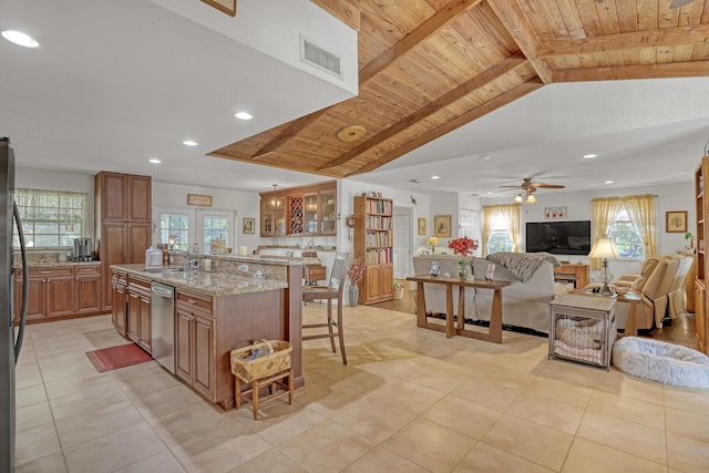 kitchen with a spacious island, a breakfast bar, sink, wooden ceiling, and light stone countertops