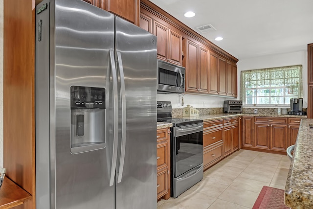 kitchen with light stone countertops, light tile patterned floors, and stainless steel appliances