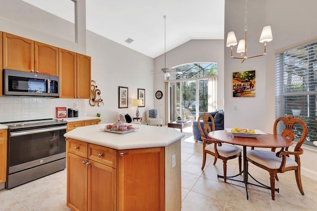 kitchen with a kitchen island, pendant lighting, tasteful backsplash, light tile patterned floors, and stainless steel appliances