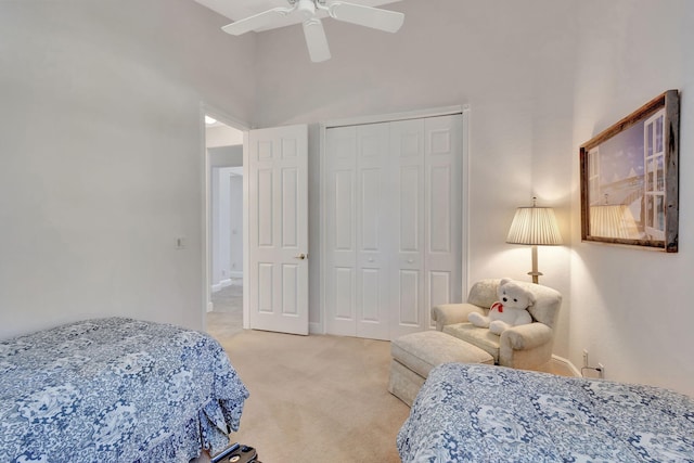 bedroom featuring a high ceiling, light colored carpet, ceiling fan, and a closet