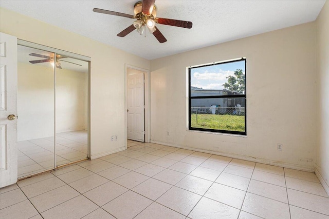 unfurnished bedroom featuring light tile patterned floors, a textured ceiling, a closet, and ceiling fan