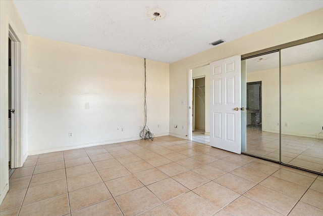 unfurnished bedroom with a textured ceiling, a closet, and light tile patterned floors