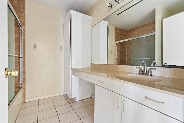 bathroom featuring tile patterned floors, shower / bath combination with glass door, vanity, and a textured ceiling