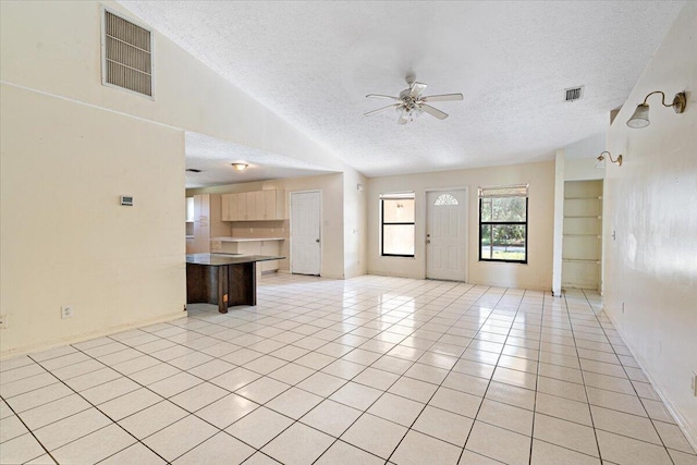 unfurnished living room with light tile patterned flooring, a textured ceiling, and ceiling fan