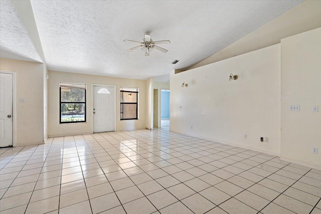 interior space with a textured ceiling, vaulted ceiling, ceiling fan, and light tile patterned flooring