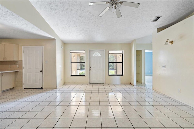 tiled entryway with ceiling fan and a textured ceiling