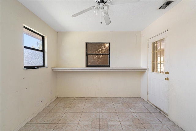 empty room featuring light tile patterned floors, a textured ceiling, and ceiling fan