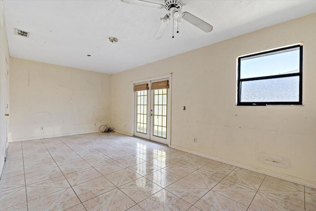 unfurnished room featuring light tile patterned flooring, ceiling fan, a textured ceiling, and french doors