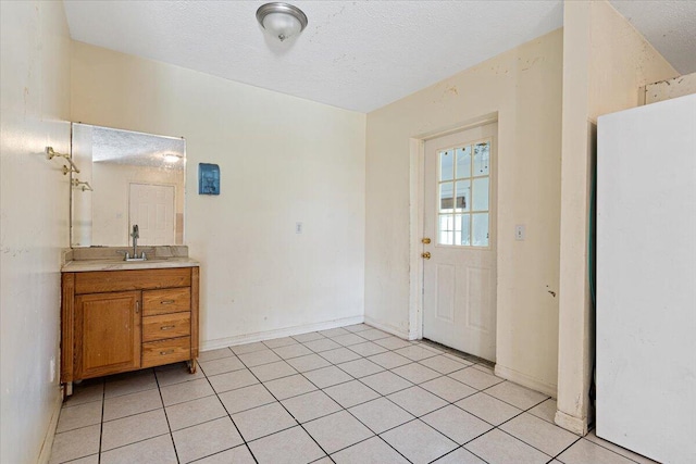 interior space featuring sink, a textured ceiling, and light tile patterned floors