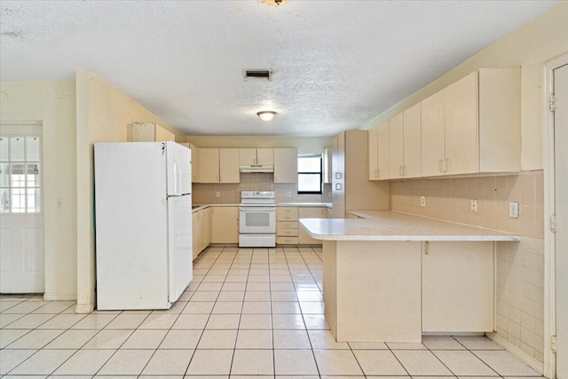 kitchen with light tile patterned floors, decorative backsplash, white appliances, and kitchen peninsula