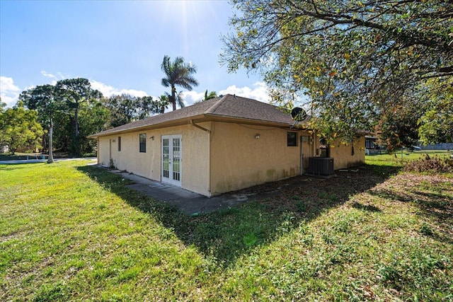 view of home's exterior featuring a yard, central air condition unit, and french doors