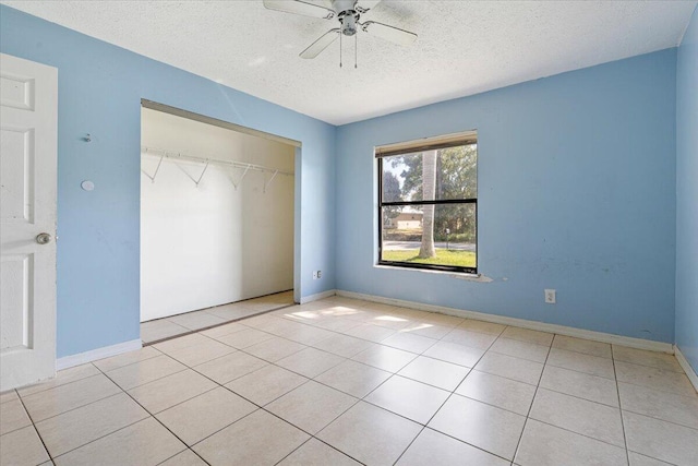 unfurnished bedroom featuring ceiling fan, light tile patterned floors, a textured ceiling, and a closet