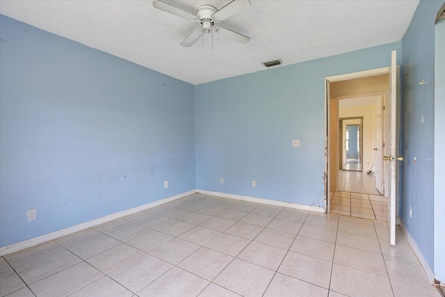 empty room with light tile patterned floors, a textured ceiling, and ceiling fan