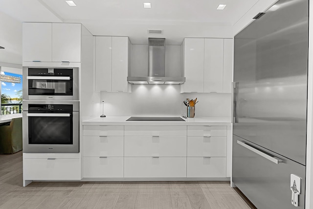 kitchen with white cabinetry, wall chimney exhaust hood, stainless steel appliances, and light wood-type flooring