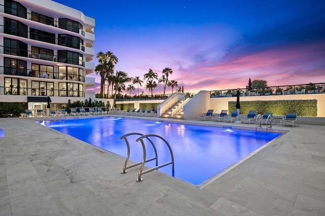 pool at dusk with a patio area