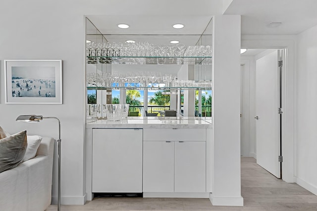 bar with fridge, light stone counters, white cabinets, and light hardwood / wood-style floors