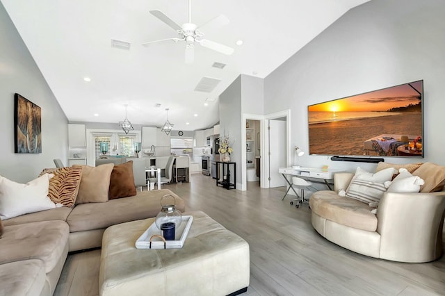 living room with high vaulted ceiling, ceiling fan, and light hardwood / wood-style flooring