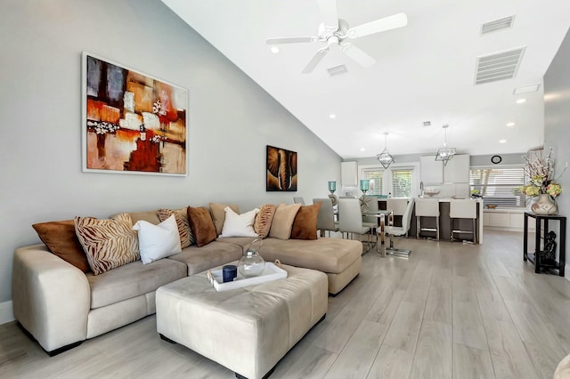 living room with vaulted ceiling, ceiling fan, and light wood-type flooring