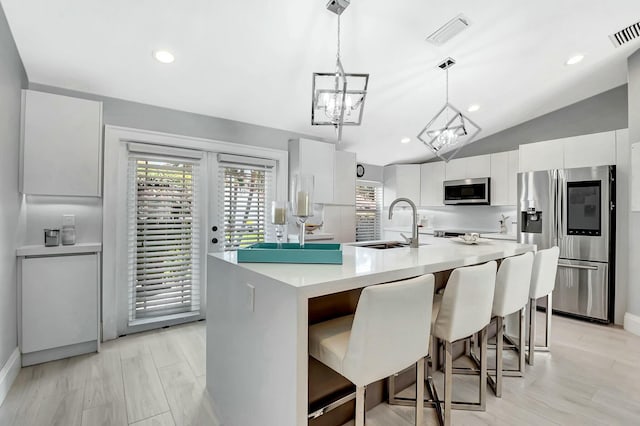 kitchen featuring stainless steel appliances, white cabinetry, sink, and pendant lighting