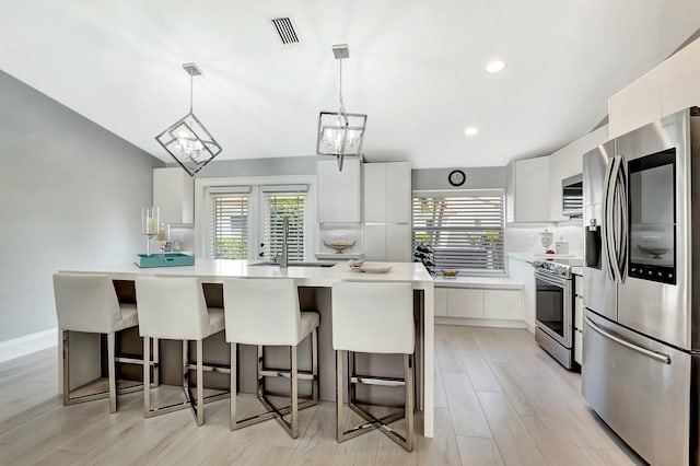 kitchen with white cabinetry, a center island, hanging light fixtures, appliances with stainless steel finishes, and plenty of natural light