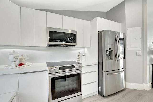 kitchen with vaulted ceiling, appliances with stainless steel finishes, electric panel, light hardwood / wood-style floors, and white cabinets