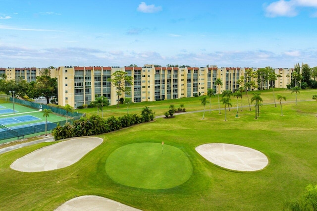 surrounding community with a yard, view of golf course, and fence