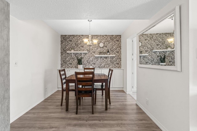 dining space with baseboards, an inviting chandelier, and wood finished floors